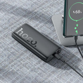 نمایی از پاوربانک هوکو J122A در حال شارژ گوشی هوشمند با نمایشگر LED فعال و طراحی مدرن